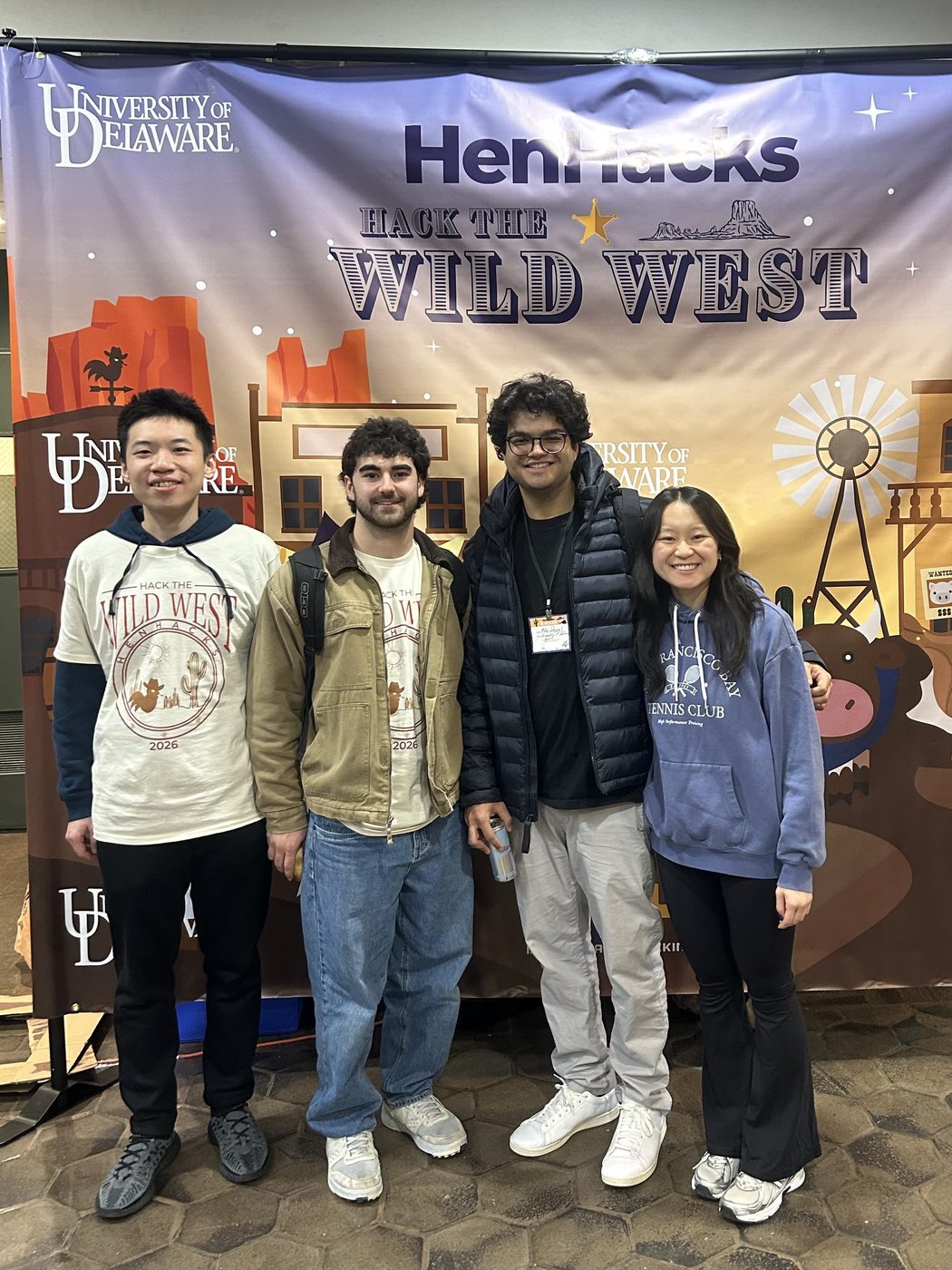 Gabe and his three teammates in front of the HenHacks 2026 Hack the Wild West backdrop at the University of Delaware